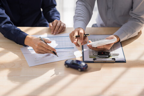 a motor dealer and customer signing a contract 